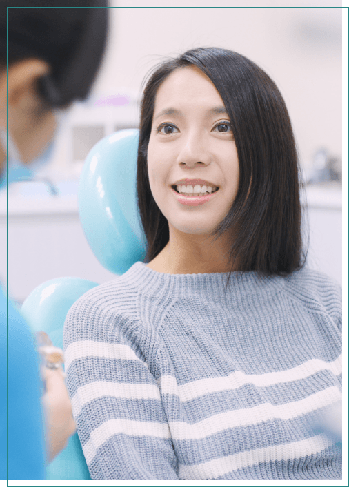 Woman in gray sweater sitting in dental chair