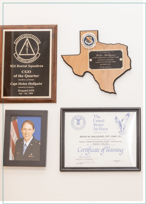 Several framed degrees plaques and photos on dental office wall