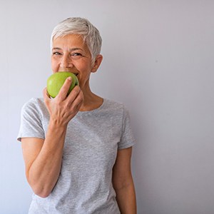 Woman smiling while biting into green apple