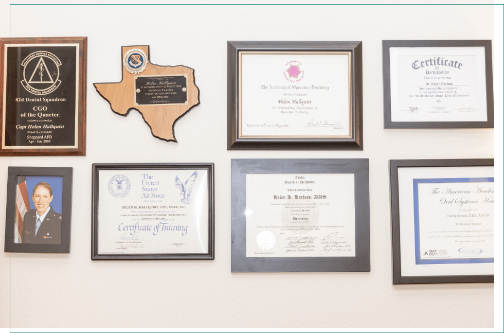 Several framed diplomas awards and photos on wall