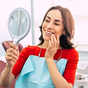 Young woman smiling in the mirror with new dental implants