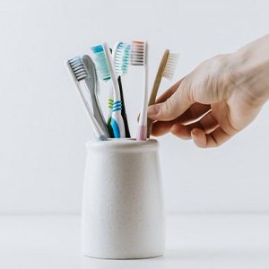 Hand reaches for toothbrush in holder